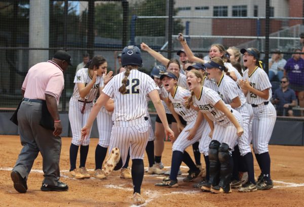 The varsity softball team gathers around home plate to celebrate another run.