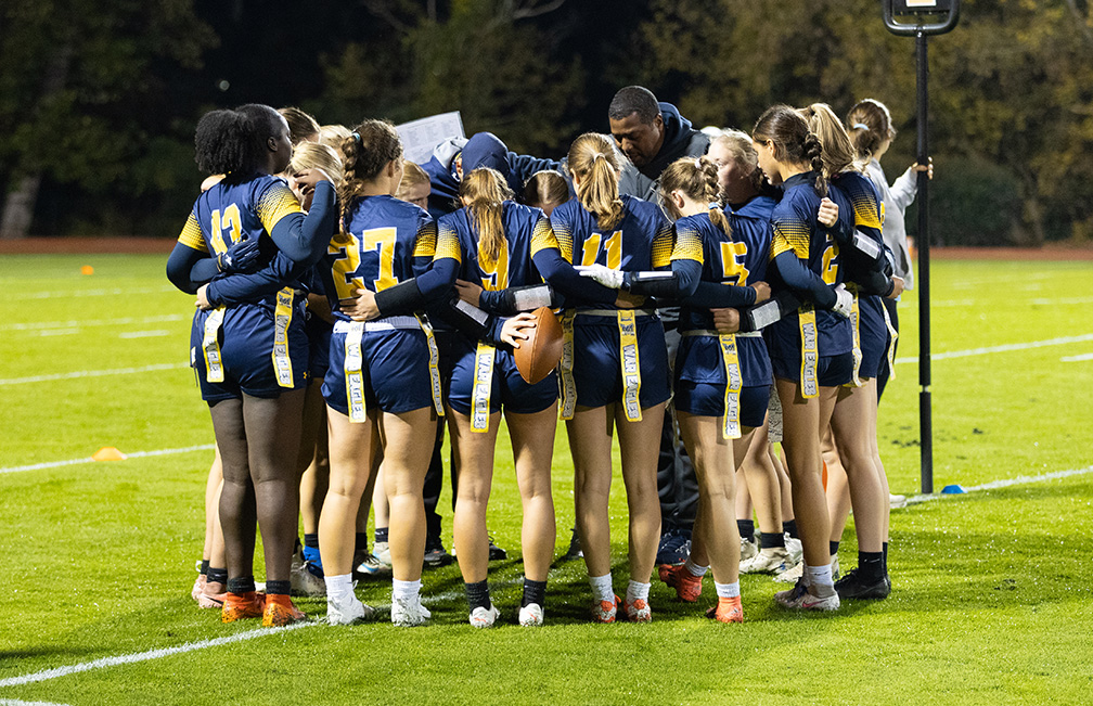 The flag football team gathers for a prayer before kickoff. Such moments formed bonds that carried the team through their very successful season.