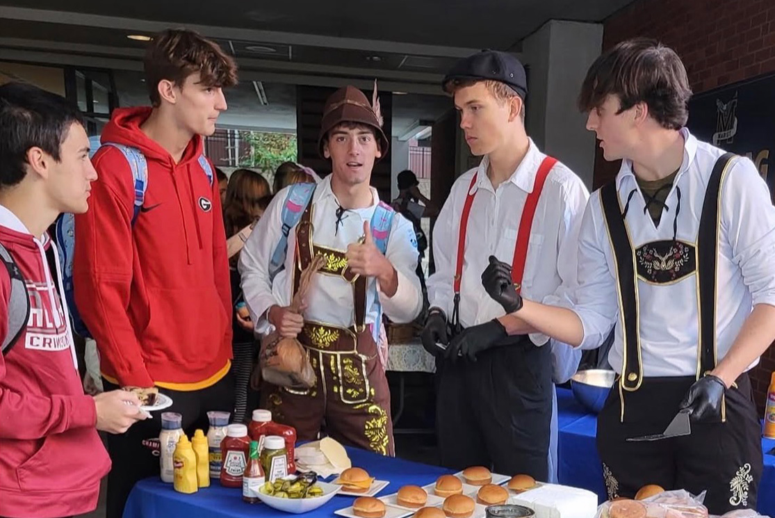 The Kitchen 101 crew, including Luke Romano, Martin Laughlin, and John David Linch, serve up smash burgers during activity period. (Contributed)